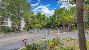 Un quartier résidentiel doté d’une entrée sécurisée, d’un immeuble à plusieurs étages et d’une pelouse bien entretenue agrémentée de diverses plantes.