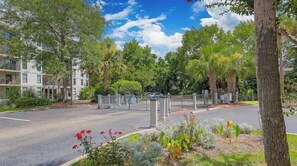 A residential area with a gated entrance, a multi-story building, and a well-maintained lawn with various plants. - Cozy Villa Near Beach Pool & Tennis on Hilton Head (Hilton Head Island)