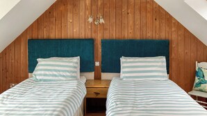 Une chambre avec deux lits, des têtes de lit en bois et un plafond en pente.