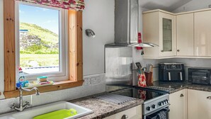 Une cuisine dotée d’une fenêtre, d’appareils électroménagers en acier inoxydable et offrant une vue sur un paysage verdoyant.