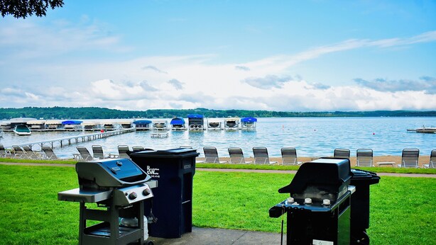 Une vue sur le lac avec un quai, des chaises longues et des barbecues.