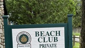 Une enseigne indiquant l’entrée d’un club de plage privé, avec un logo et le nom « Shanty Creek ».