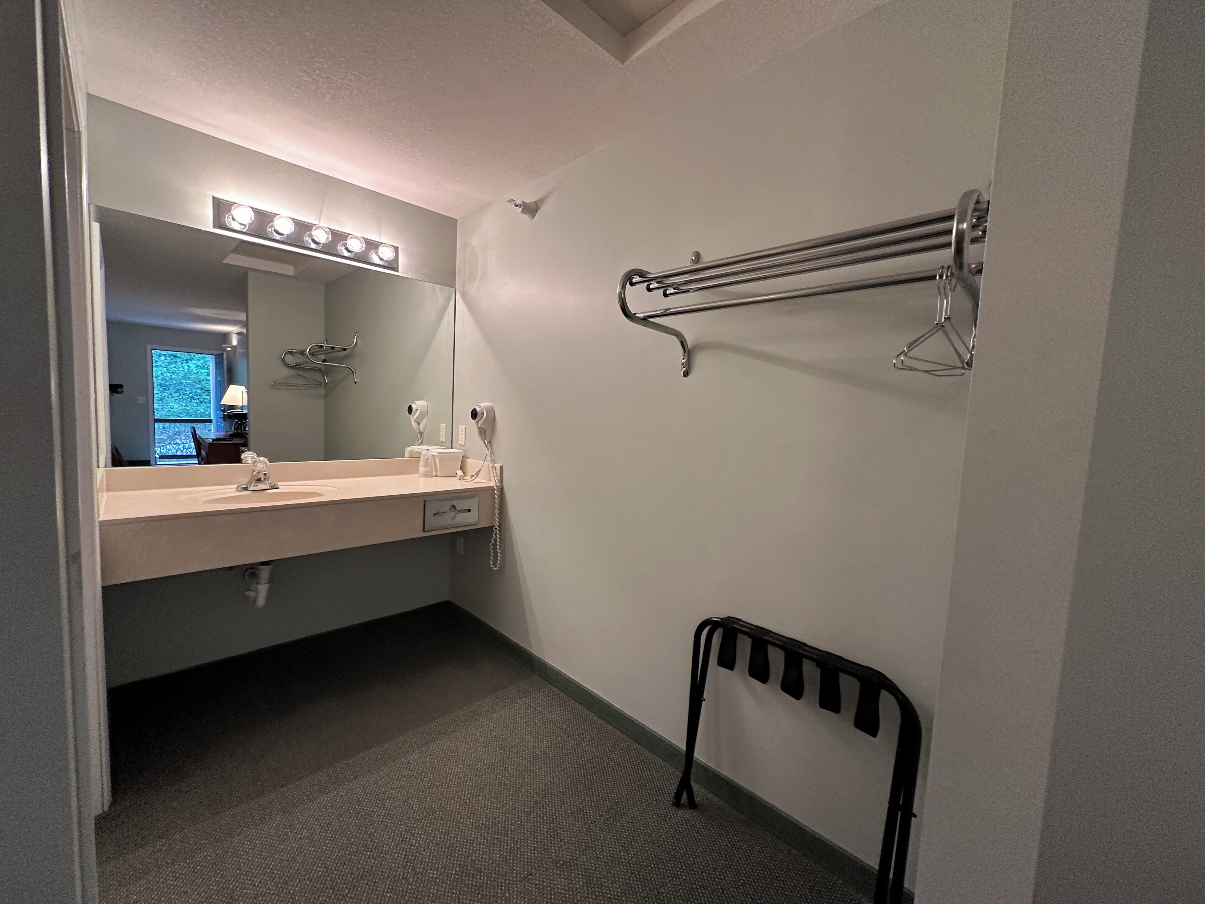 Une salle de bain avec un lavabo, un miroir, un porte-serviettes et une chaise noire.
