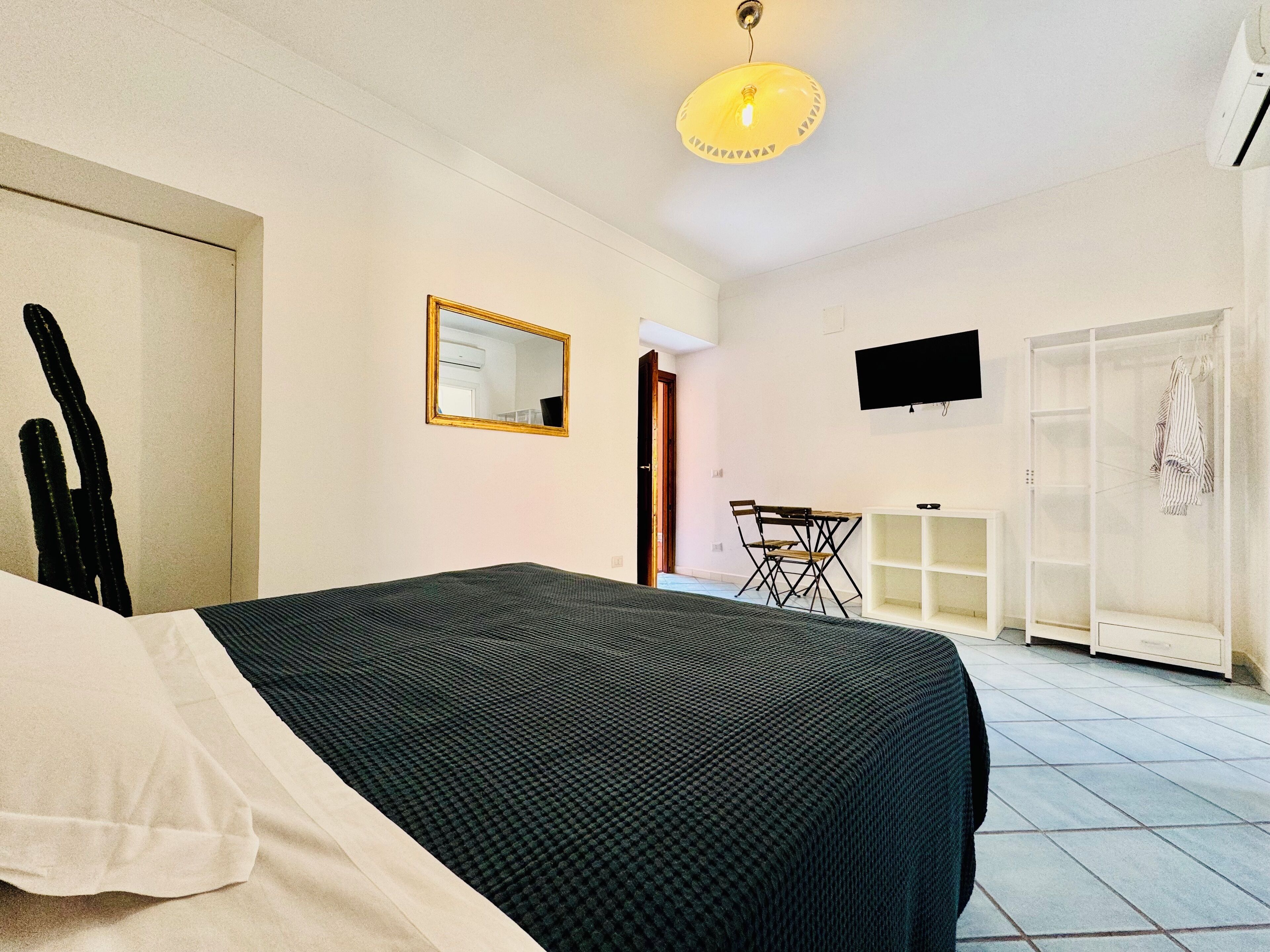 A bedroom with a bed, a desk, a chair, a TV, and a wardrobe.