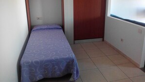 Une petite chambre avec un lit simple, une armoire en bois et une fenêtre donnant sur un beau paysage.
