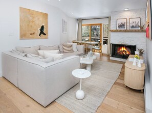 A modern living room with a large sofa, a fireplace, and a dining area. - Fallridge 401 | 3BR Top-Floor Vail Condo, Hot Tub (Vail)