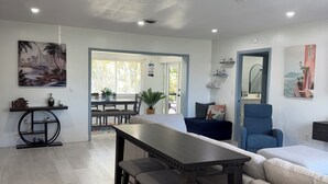 Un salon moderne avec une table à manger en bois foncé, un canapé beige et un fauteuil bleu.