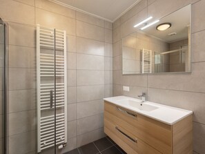 Ein modernes Badezimmer mit einem weißen Waschtisch, einem Spiegel und einem Handtuchhalter.