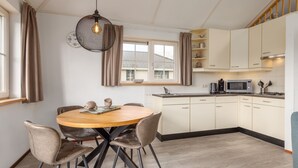 Una cucina moderna con mobili bianchi, un tavolo rotondo con sedie e una lampada a sospensione.