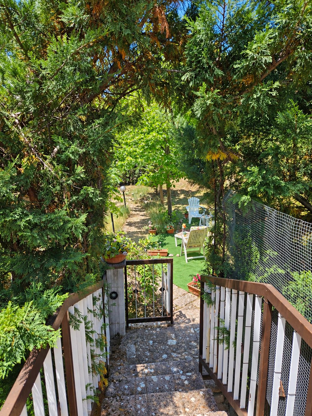 A garden pathway leading to a seating area with a table and chairs.