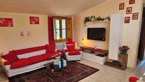Ein Wohnzimmer mit einem roten und weißen Sofagarnitur, einem Couchtisch, einem Fernseher und einem Kamin.