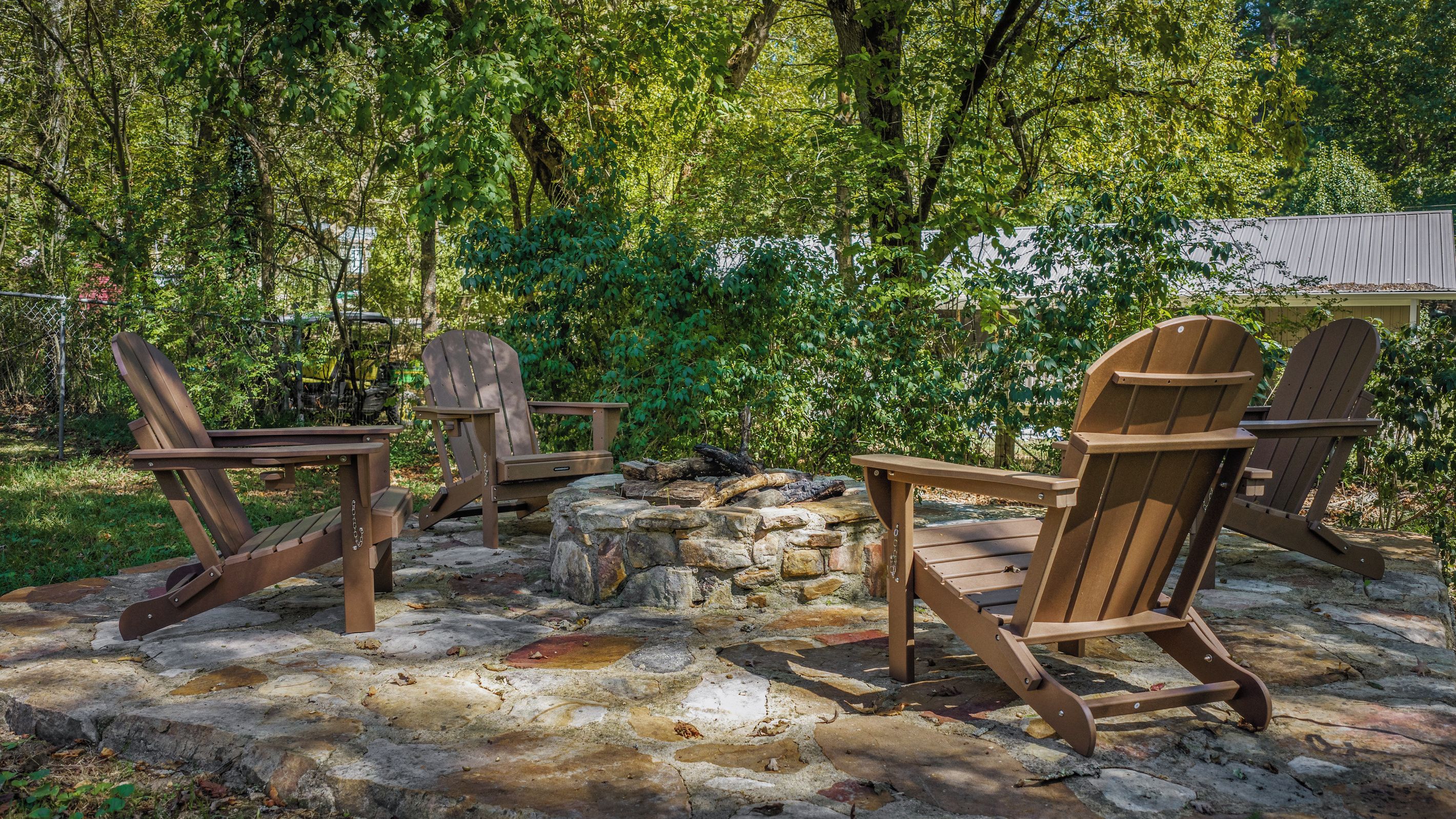 A stone fire pit area with Adirondack chairs.