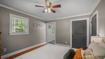 A room with a ceiling fan, a door labeled 'COTTAGE', and a window with blinds.