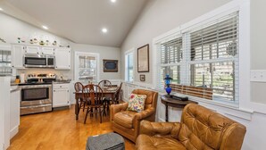 A kitchen with white cabinets, stainless steel appliances, and a dining area with wooden chairs and a table.