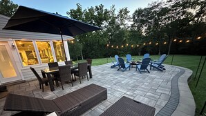 Eine Terrasse mit Esstisch und Stühlen, einem überdachten Sitzbereich und einer Lichterkette.