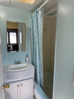 Un baño con un lavabo blanco, un espejo, una cortina de ducha y una puerta.