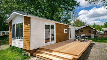 Enjoy a cozy stay in this compact mobile home with a spacious deck and easy access via a wooden ramp.