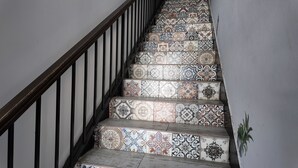 A staircase with a black metal railing and a variety of patterned tiles. - Meydan otel (Cesme)