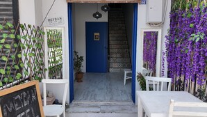 A narrow entrance to a building with a blue door, a staircase, and a sign reading "MEYLAN Boutique Hotel". - Meydan otel (Cesme)