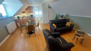 Un espacio habitable compacto con comedor, un sofá de cuero negro y una mesita auxiliar pequeña.