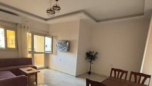 A spacious living area with a sofa, a dining table with chairs, and a ceiling fan. - Wake up looking at the Red Sea! (Hurghada)
