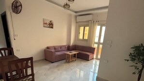 A spacious living area with a sofa, a small table, and a dining table with chairs. - Wake up looking at the Red Sea! (Hurghada)