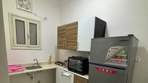 A compact kitchen with a sink, a microwave, a refrigerator, and wooden cabinets. - Wake up looking at the Red Sea! (Hurghada)