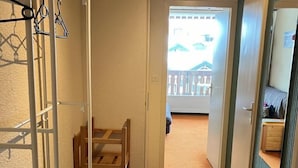 Ein Flur mit einer Holzbank, einem Kleiderständer und einem kleinen Tisch.