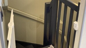 A staircase with a white handrail and a black baluster, leading to a landing with a light fixture and a wall-mounted picture.