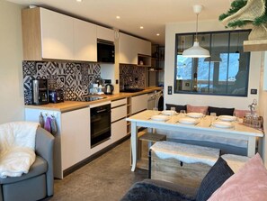 A modern kitchen with white cabinets, patterned backsplash, and a dining area with a table set for four. - 20m from ski slopes, 12nd floor, view valley, balcony, tv, ski locker, 50m², Avoriaz (Avoriaz)