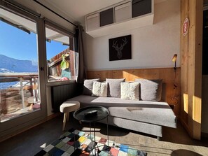 A cozy room with a sofa, a small table, and a window overlooking a snowy landscape. - 200m from resort center, 5th floor, balcony, tv, ski locker, 26m², Avoriaz (Avoriaz)