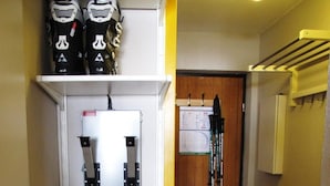 A narrow hallway with a white storage unit on the left, a wooden door at the end, and a rack with skis on the right. - 10m from ski slopes, 3rd floor, tv, ski locker, 21m², Avoriaz (Avoriaz)