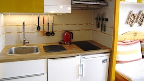 A compact kitchen with a sink, a microwave, and a kettle. There are utensils hanging on the wall and a bed with a striped pillow in the adjacent room. - 10m from ski slopes, 3rd floor, tv, ski locker, 21m², Avoriaz (Avoriaz)