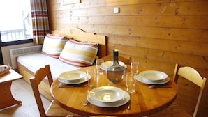 A wooden dining table set with plates, glasses, and a pitcher, surrounded by wooden chairs in a room with a bed and a window with curtains. - 10m from ski slopes, 3rd floor, tv, ski locker, 21m², Avoriaz (Avoriaz)