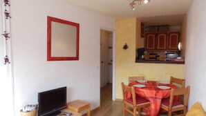 A compact living space with a television, a small table, a dining area with a table and chairs, and a kitchen area with cabinets and a microwave. - 50m from ski slopes, 6th floor, view resort, balcony, tv, ski locker, 32m², Avoriaz (Avoriaz)