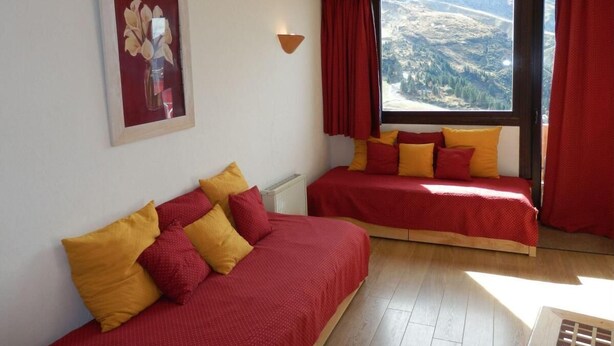 A room with two beds, red and yellow bedding, a framed picture on the wall, and a window with a mountain view. - 50m from ski slopes, 6th floor, view resort, balcony, tv, ski locker, 32m², Avoriaz (Avoriaz)