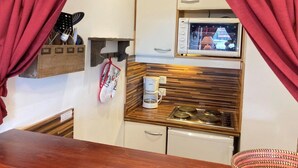 A compact kitchenette with a microwave, coffee maker, and wooden countertop.
