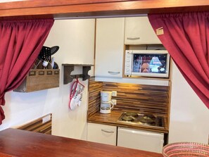 Eine kleine Küchenzeile mit Mikrowelle, Kaffeemaschine und Holz Arbeitsplatte.
