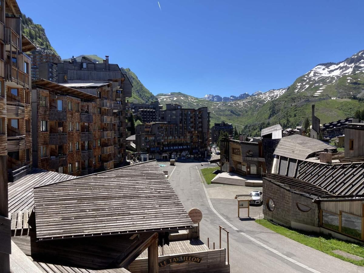 A mountain town with wooden buildings, a road, and snow-capped mountains in the background.