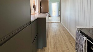 A modern kitchen with a central island, wooden flooring, and a view into the dining area.
