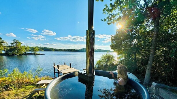 A hot tub with a wooden deck and a wooden structure extending into a lake.