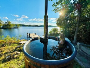 Un jacuzzi con cubierta de madera y estructura de madera que se adentra en un lago.