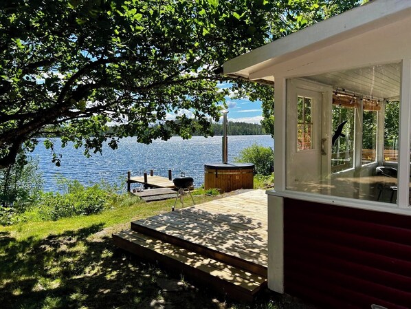 Una cabaña junto al lago con terraza, jacuzzi y parrilla.