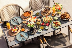 Ein Tisch reichhaltig mit Speisen gedeckt, darunter Salate, Fleisch und Käse, was auf ein Buffet hindeutet.