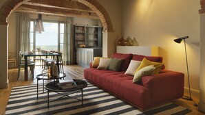 A living room with a red sofa, striped rug, and a dining area with a table and chairs.