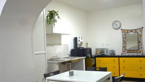 A compact kitchen with a white table and chairs, a yellow cabinet, and a clock on the wall. - Apartment Lallarella 17: historic center of Naples (Napoli)