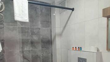 Un baño moderno con cabina de ducha de vidrio, inodoro y lavamanos con espejo.