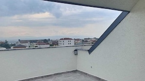 Un balcón con una mesa y sillas, con vistas a un cuerpo de agua y edificios.