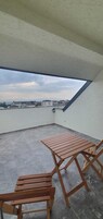 Un balcón con una mesa y sillas, con vistas a un cuerpo de agua y edificios.