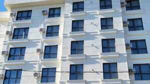 Un hotel de varios pisos llamado "PETRA PORT" con una fachada simétrica, unidades de aire acondicionado y una entrada central con escalones.